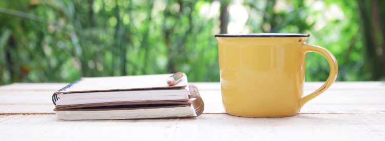 Notebook and yellow mug on table